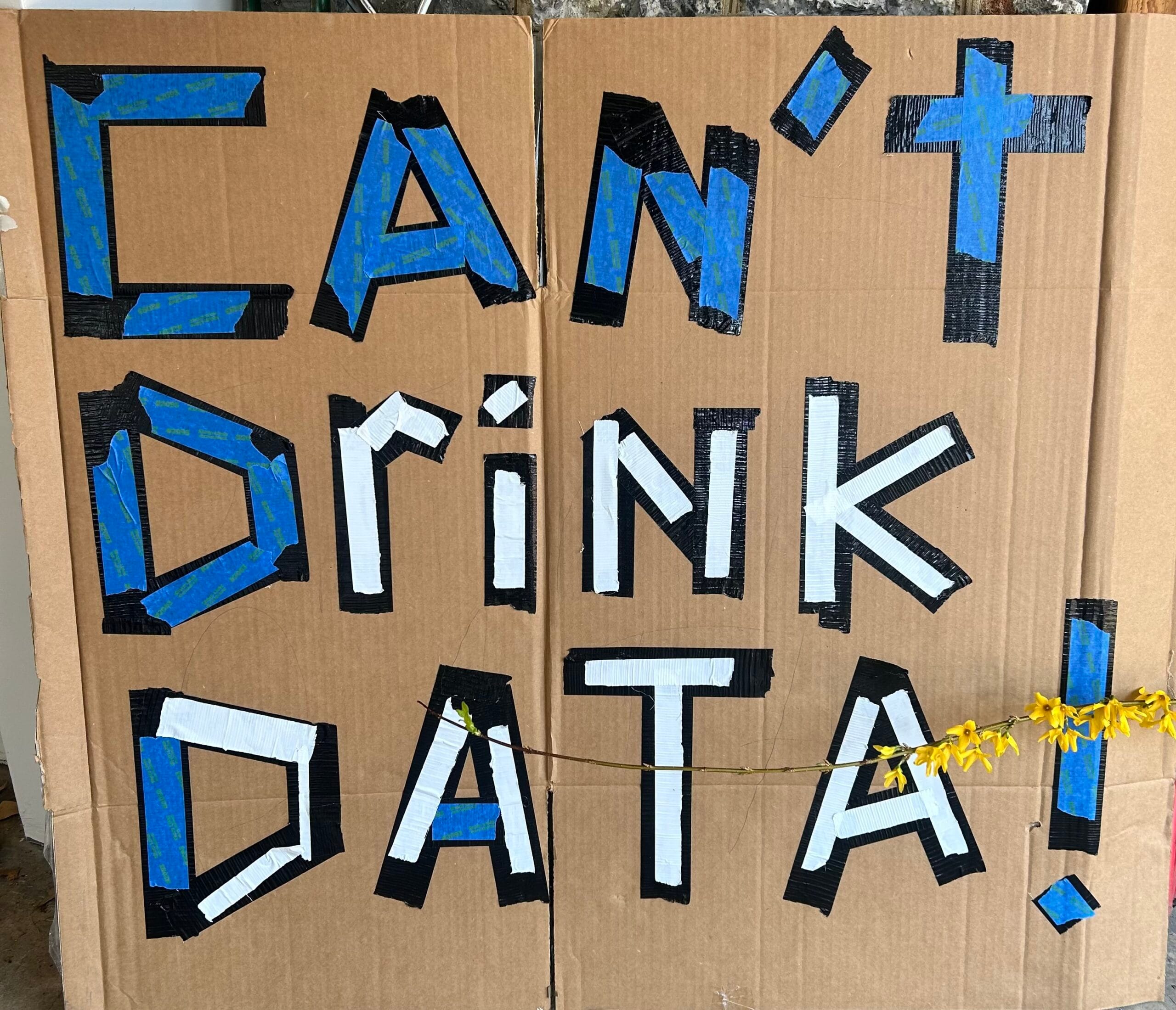 Duct tape letter on cardboard read, "Can't Drink Data"